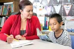 Student with teacher reading book